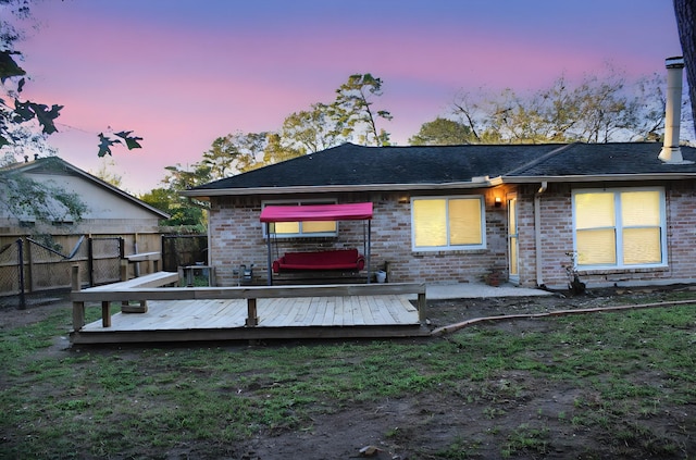 back house at dusk with a wooden deck