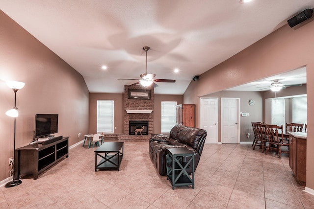 tiled living room featuring a wealth of natural light, a fireplace, ceiling fan, and lofted ceiling