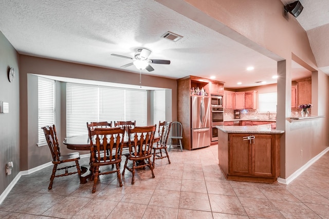 tiled dining space featuring ceiling fan, sink, and a textured ceiling