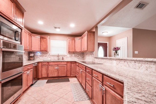 kitchen featuring backsplash, light stone counters, a healthy amount of sunlight, and sink