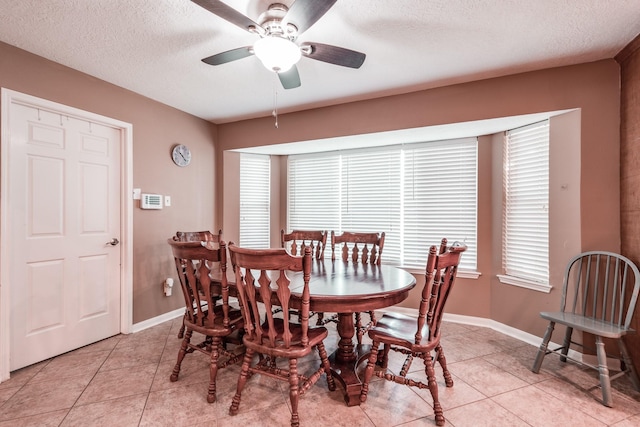 tiled dining area with ceiling fan and a textured ceiling