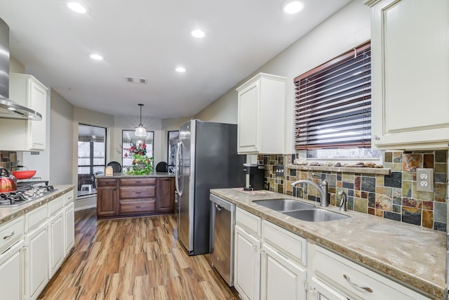 kitchen with appliances with stainless steel finishes, sink, light hardwood / wood-style flooring, white cabinets, and hanging light fixtures