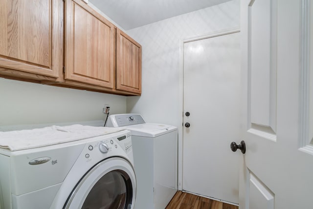 clothes washing area with washer and clothes dryer, dark hardwood / wood-style flooring, and cabinets