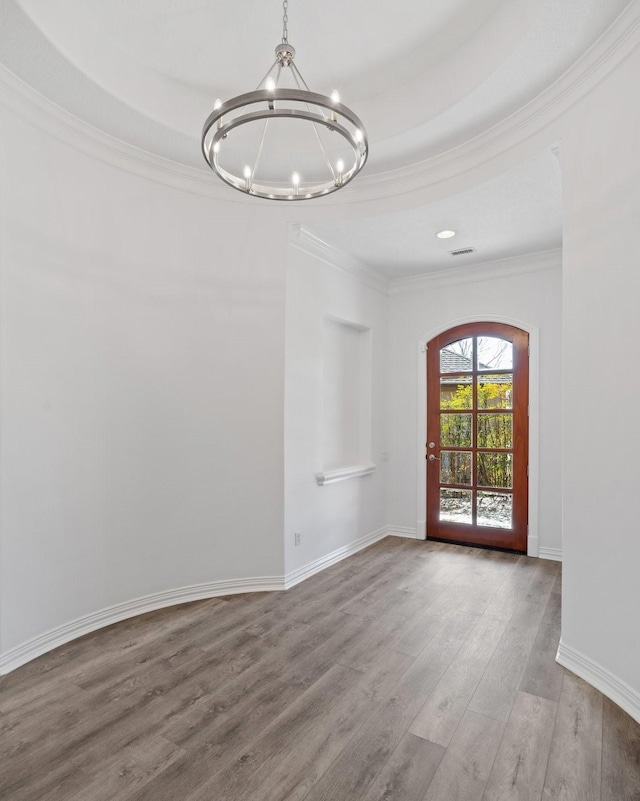 unfurnished room with hardwood / wood-style floors, an inviting chandelier, and crown molding