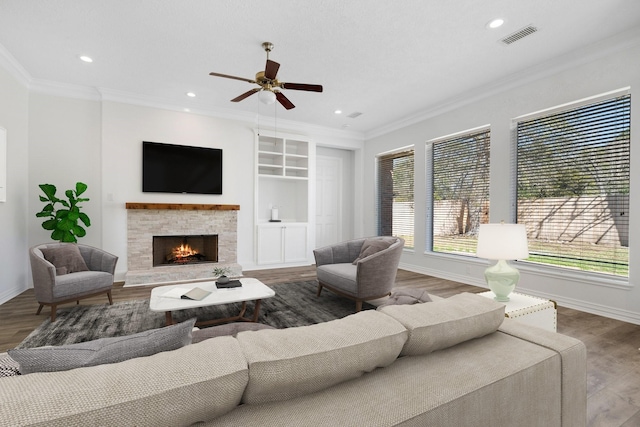 living room featuring hardwood / wood-style floors, a stone fireplace, and ornamental molding