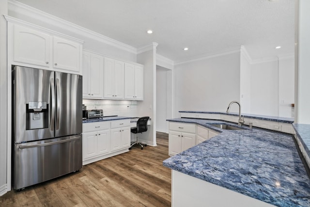 kitchen with stainless steel refrigerator with ice dispenser, dark wood-type flooring, sink, built in desk, and white cabinetry