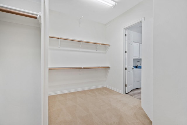 walk in closet featuring washer / dryer and light colored carpet