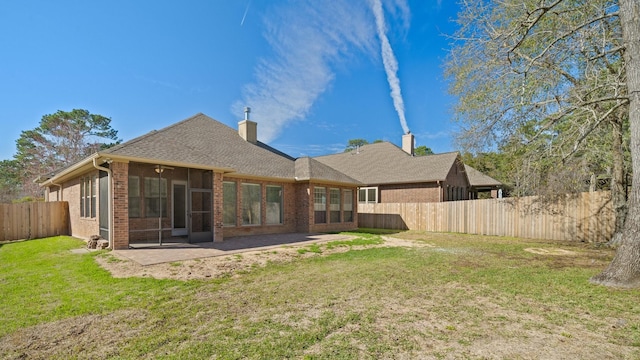 back of house with a lawn, a sunroom, and a patio