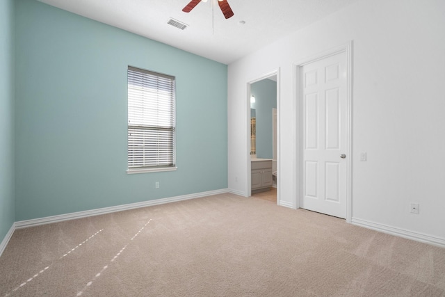 unfurnished bedroom featuring ceiling fan, light colored carpet, and connected bathroom