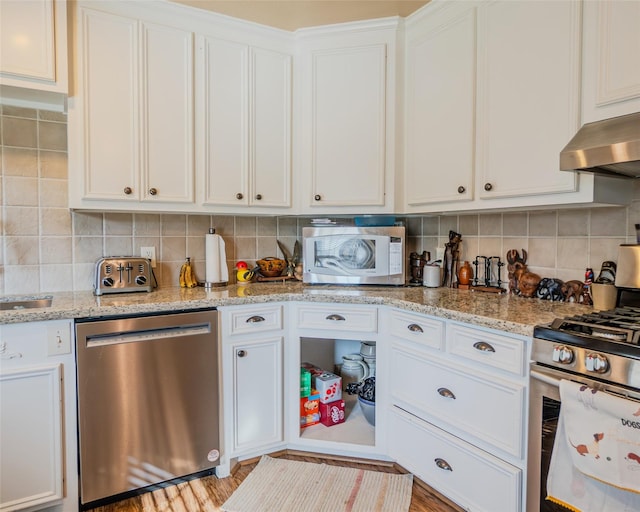 kitchen with stainless steel appliances, white cabinetry, light stone counters, light hardwood / wood-style floors, and decorative backsplash