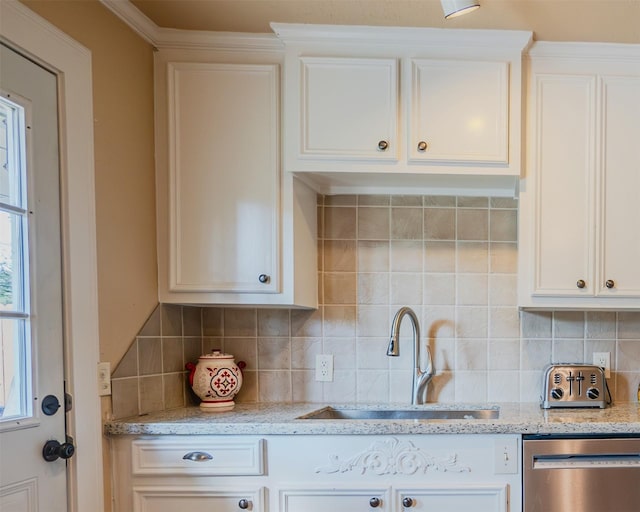 kitchen featuring white cabinets, dishwasher, tasteful backsplash, and sink