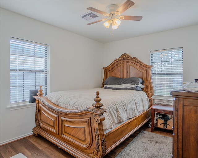 bedroom featuring dark hardwood / wood-style flooring, ceiling fan, and multiple windows