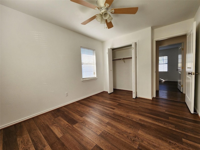 unfurnished bedroom featuring dark wood-type flooring, ceiling fan, a closet, and multiple windows