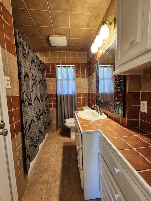 bathroom with tile walls, tile patterned flooring, toilet, and vanity