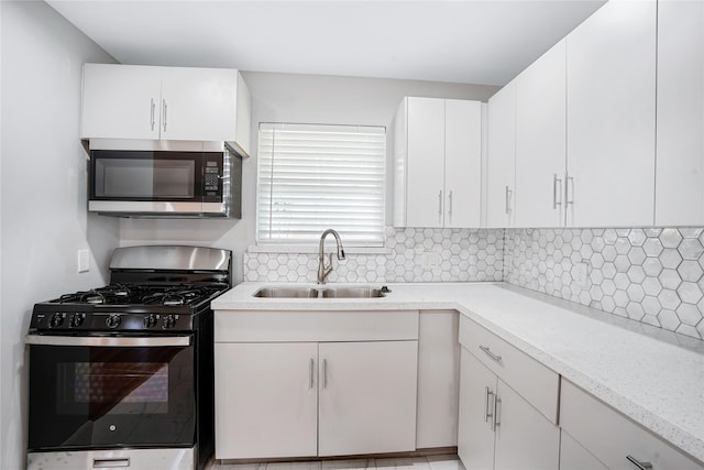 kitchen with decorative backsplash, sink, white cabinets, and appliances with stainless steel finishes