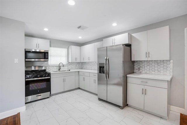 kitchen with decorative backsplash, stainless steel appliances, white cabinetry, and sink