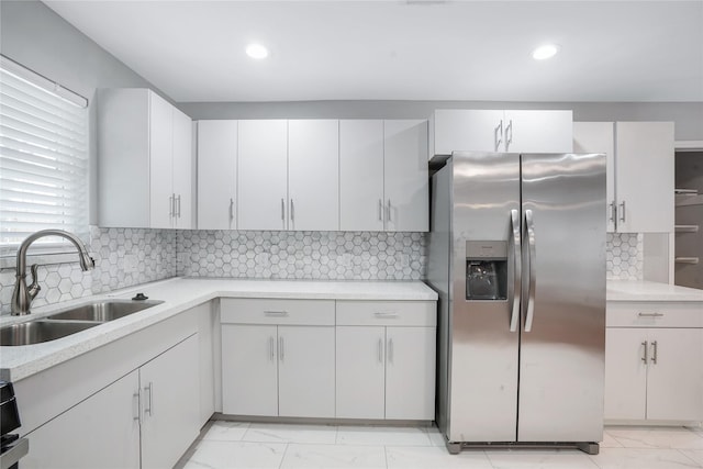 kitchen with white cabinets, stainless steel fridge, sink, and tasteful backsplash