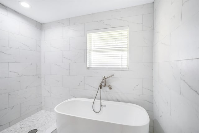 bathroom featuring plus walk in shower and tile walls