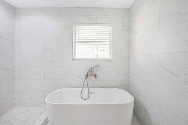 bathroom with a bathing tub and tile walls