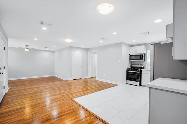 kitchen featuring backsplash, white cabinets, ceiling fan, appliances with stainless steel finishes, and light hardwood / wood-style floors