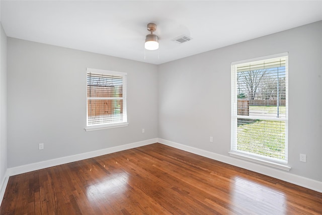 empty room with ceiling fan, plenty of natural light, and hardwood / wood-style floors