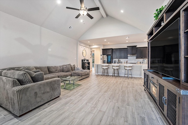 living room featuring beamed ceiling, high vaulted ceiling, light hardwood / wood-style flooring, and ceiling fan