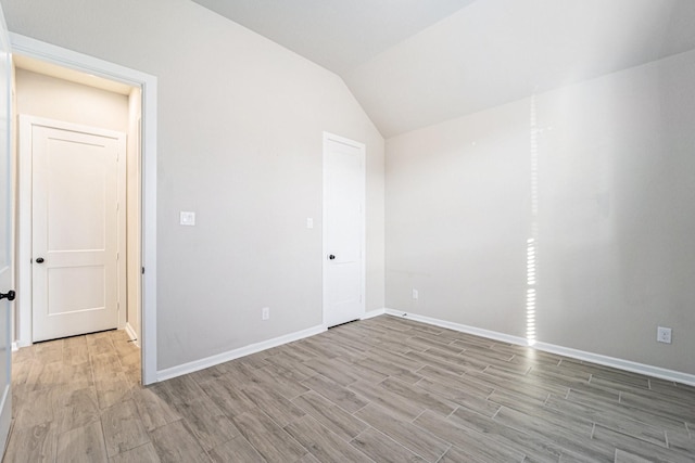 spare room with lofted ceiling and light wood-type flooring