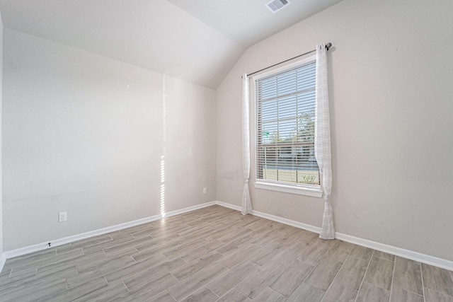 unfurnished room featuring plenty of natural light, vaulted ceiling, and light wood-type flooring