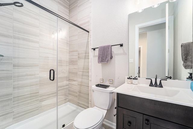 bathroom featuring vanity, toilet, and a shower with shower door