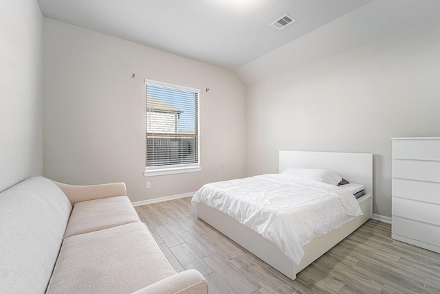 bedroom with light hardwood / wood-style floors and lofted ceiling