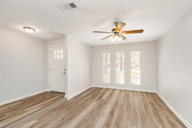 empty room with ceiling fan, light wood-type flooring, and a textured ceiling