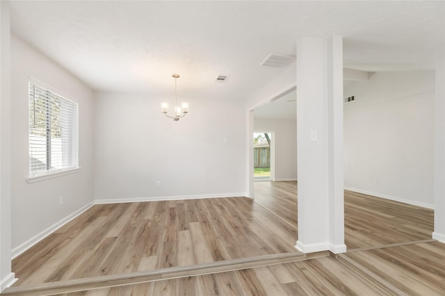 spare room featuring lofted ceiling, light hardwood / wood-style floors, and a notable chandelier