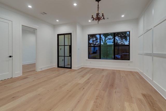 unfurnished room with ornamental molding, light hardwood / wood-style floors, and a notable chandelier