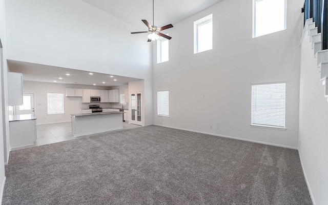 unfurnished living room with light colored carpet and ceiling fan