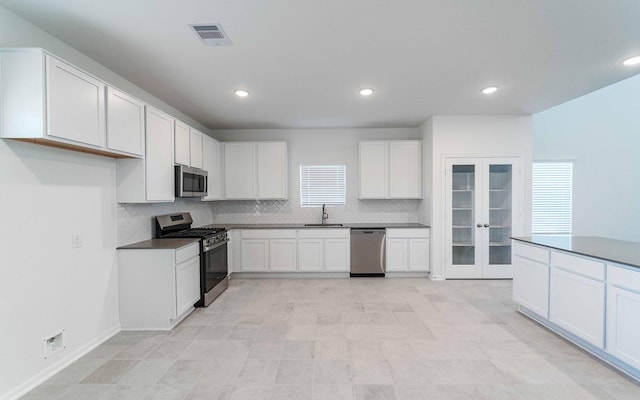 kitchen with sink, white cabinetry, stainless steel appliances, tasteful backsplash, and french doors