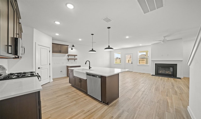 kitchen with pendant lighting, a center island with sink, sink, dark brown cabinetry, and stainless steel appliances