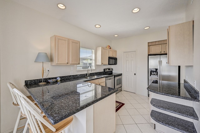 kitchen featuring kitchen peninsula, a kitchen breakfast bar, dark stone counters, stainless steel appliances, and sink