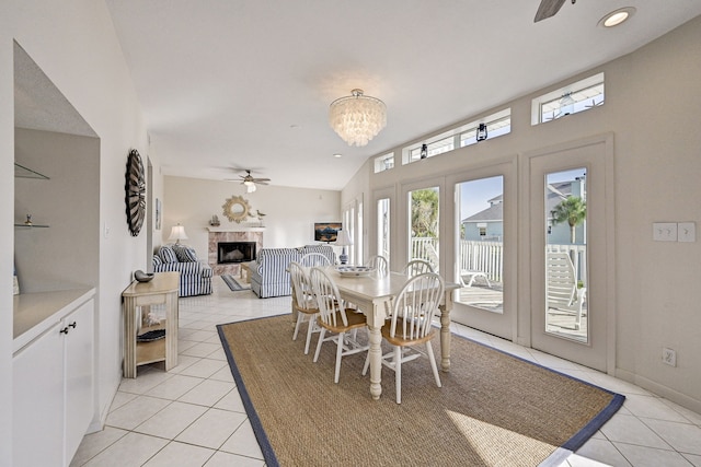 dining area with light tile patterned floors, ceiling fan with notable chandelier, and vaulted ceiling