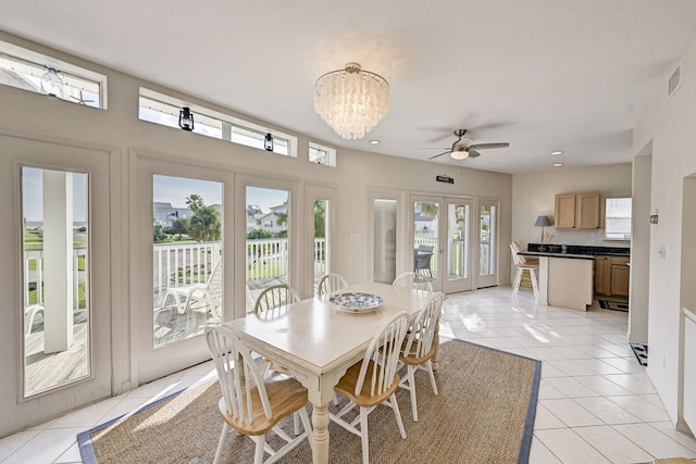 dining space with french doors, ceiling fan with notable chandelier, and light tile patterned flooring