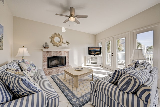 living room featuring ceiling fan, french doors, vaulted ceiling, a fireplace, and light tile patterned floors