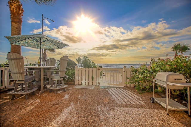 patio terrace at dusk featuring area for grilling and a water view