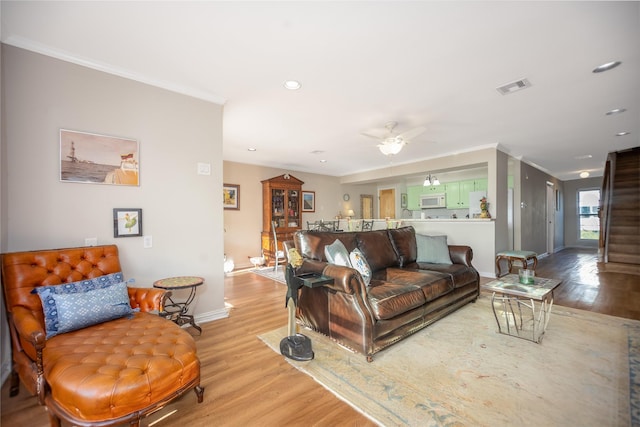 living room featuring light wood-type flooring, ceiling fan, and crown molding