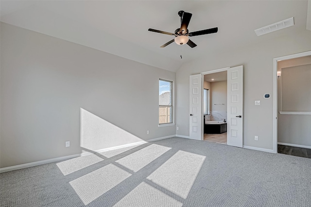 unfurnished bedroom featuring carpet, ceiling fan, ensuite bathroom, and vaulted ceiling