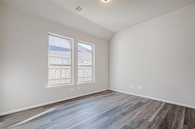 spare room with hardwood / wood-style floors and lofted ceiling