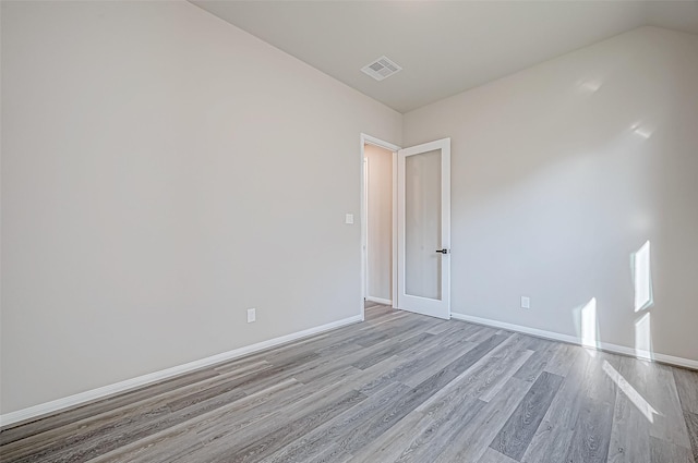 spare room with light hardwood / wood-style floors and lofted ceiling