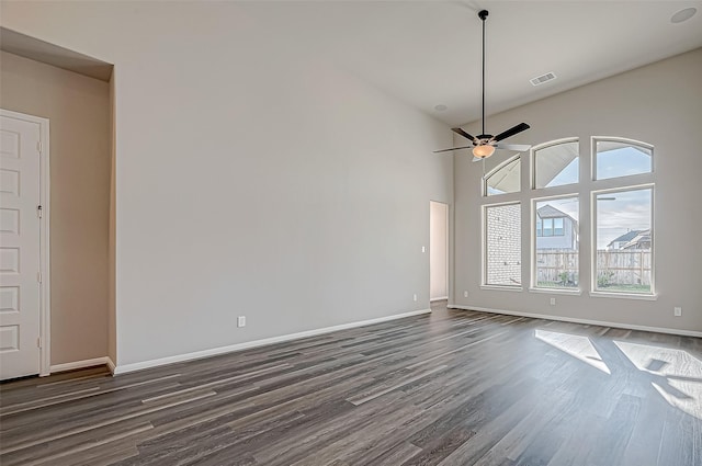 empty room with ceiling fan, dark wood-type flooring, and a high ceiling