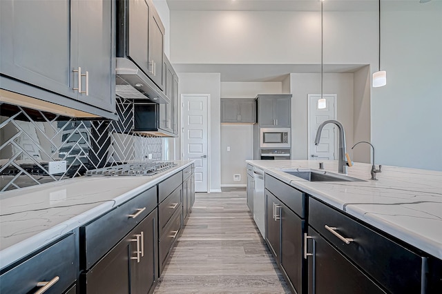 kitchen with stainless steel appliances, sink, decorative light fixtures, light hardwood / wood-style flooring, and gray cabinets