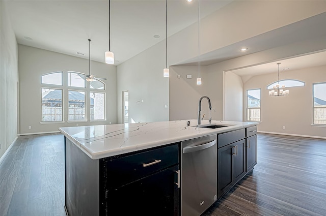 kitchen with stainless steel dishwasher, a healthy amount of sunlight, an island with sink, and pendant lighting