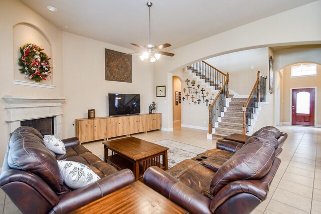 living room with ceiling fan, light tile patterned floors, and a tile fireplace