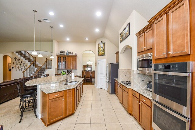 kitchen featuring pendant lighting, sink, a breakfast bar area, light stone counters, and stainless steel appliances